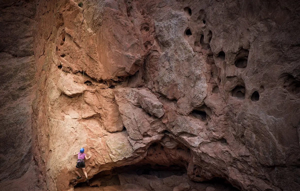 A climber on a steep red sandstone wall